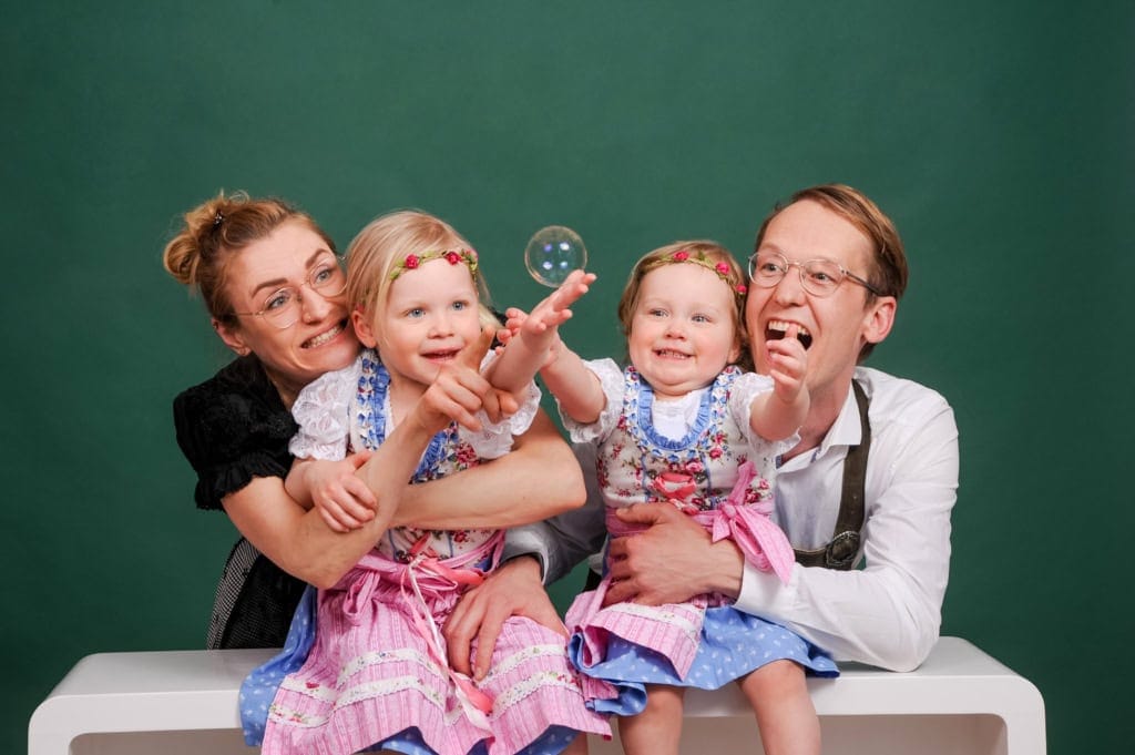 Happy family playing with soap bubbles, children and parents in traditional costume