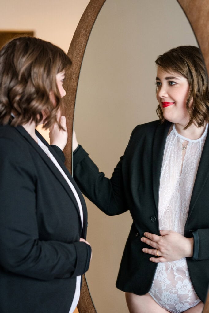 Porträt einer jungen Frau beim Blick in den Spiegel, im Business-Outfit, während sie sich auf professionelle Fotos vorbereitet, typische Motive für Fotografien bei Photogenika in München.