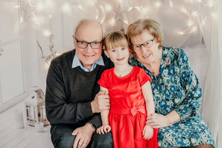 Lustiges Familienporträt im Fotostudio München mit Großeltern und Enkelin, schöne Weihnachtsdekoration, professionelle Baby- und Familienfotografie, festliches Ambiente, hochwertiger Fotodruck, unvergessliche Erinnerungen.