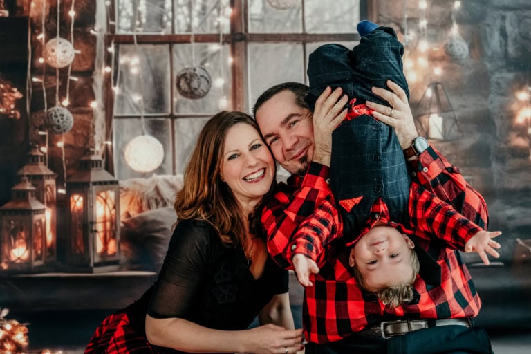 Familienfoto mit lachendem Paar und kleinem Kind im festlichen Weihnachtssetup, festliche Stimmung, professionelle Familienfotografie in München, hochwertiges Fotostudio, joyfulles Weihnachtsfoto.