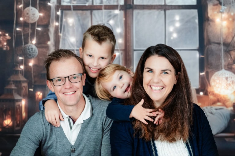 Familienporträt in München im Photogenika Fotostudio mit fröhlicher Familie und weihnachtlicher Dekoration, professionelle Familienfotografie für besondere Momente, Fotostudio München.