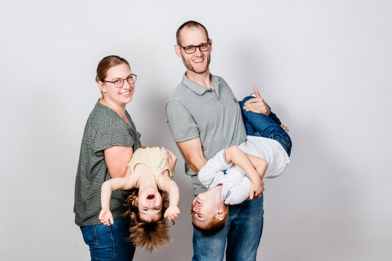 Laughing family with two children, professional studio photography, family portrait, neutral background, friendly atmosphere, high-quality images, for family photos, family time, children's photography, Munich.