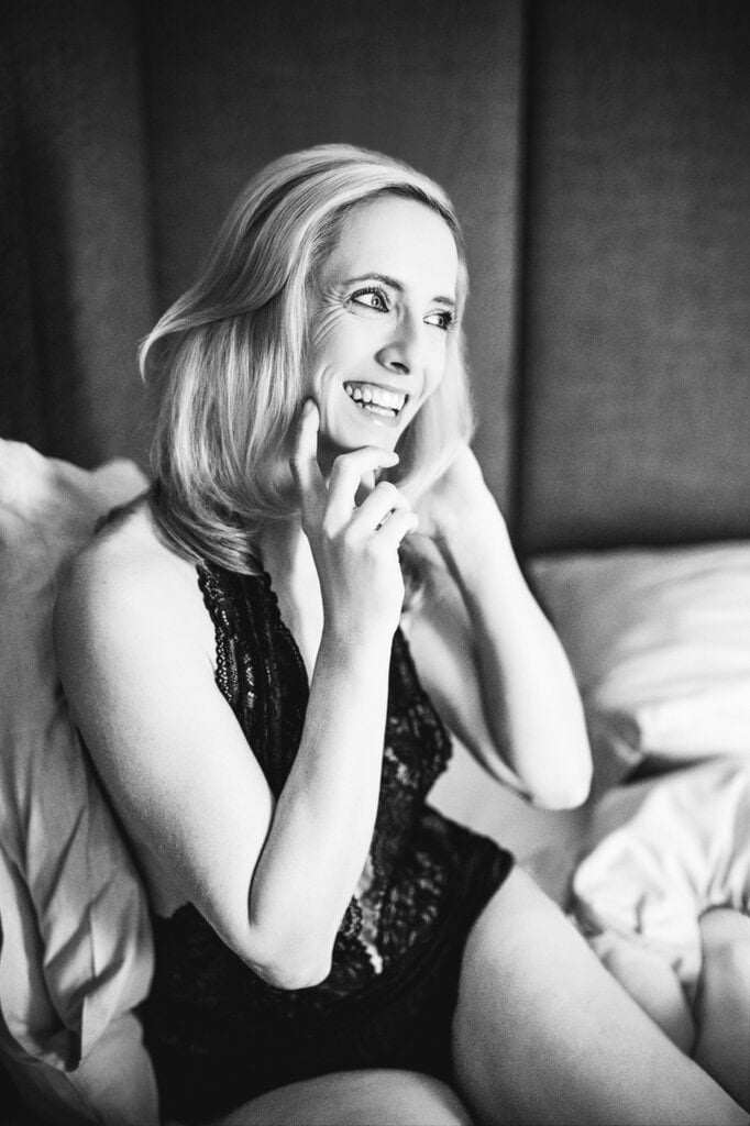 Lachende Frau in schwarzem Spitzenbody auf einem Bett