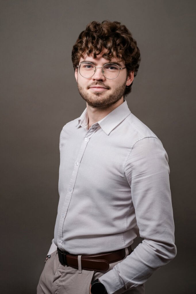 Young man with glasses and curly hair, wearing a white shirt, for a job interview.