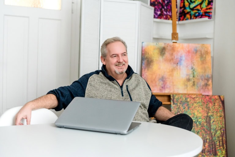1. High-quality portrait photo of a laughing man in front of an art wall in a photo studio in Munich.