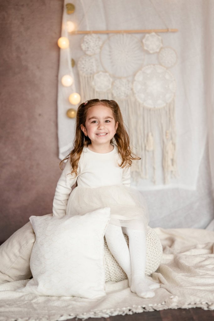 Ein Mädchen sitzt auf einem Pouf vor einer Traumfänger-Dekoration.