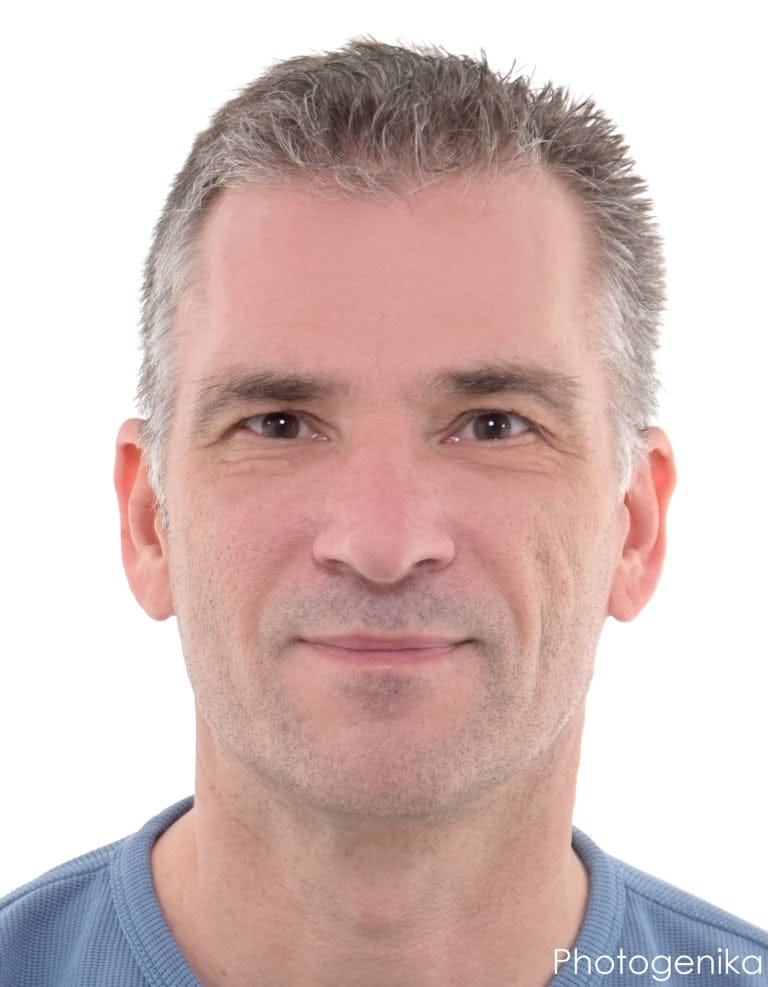 Biometrisches Passbild eines Mannes mit grauen Haaren im blauen Shirt.