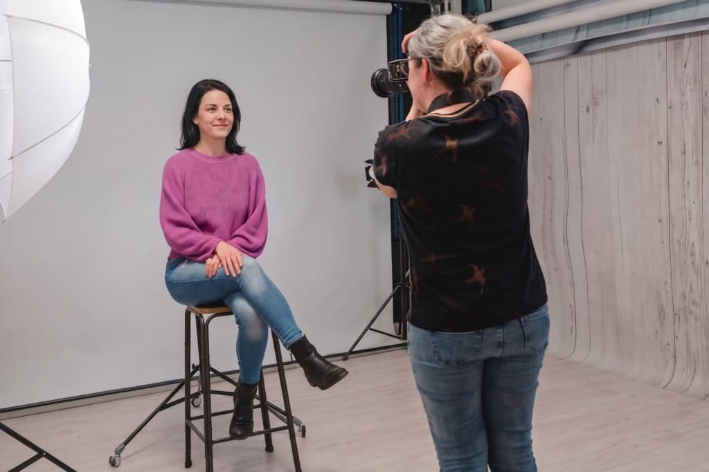 Fotografin macht ein Passfoto einer jungen Frau in einem Fotostudio in München.